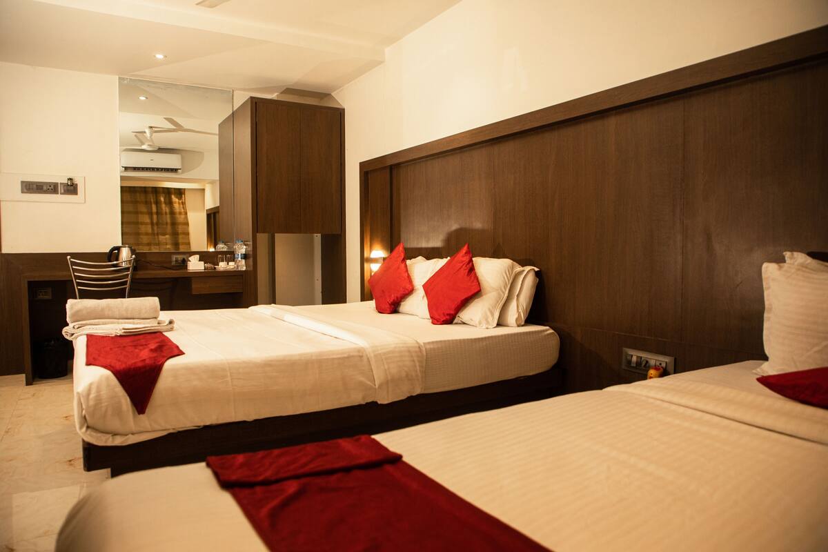 Habitación de hotel con dos camas, un escritorio, un espejo y un ventilador de techo.