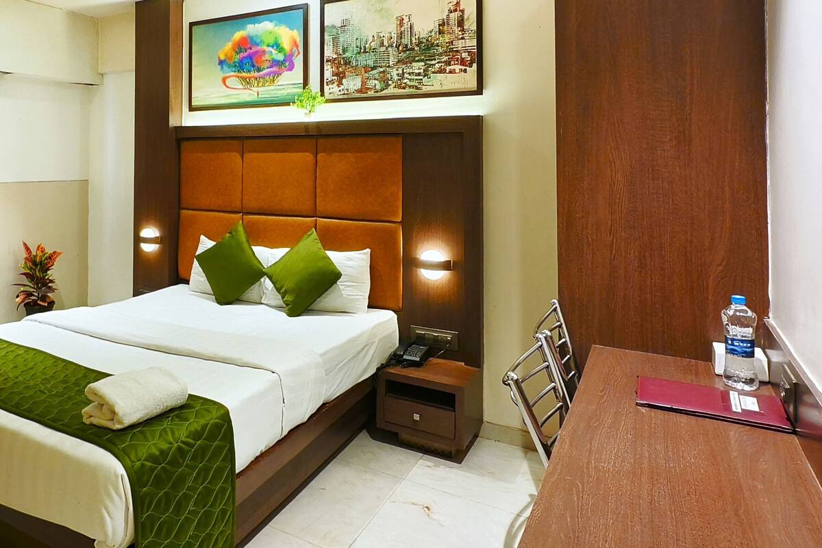 Una habitación de hotel con cama, mesita de noche, escritorio y baño.