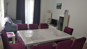 Un coin repas comprenant une table et des chaises, un téléviseur et un meuble.