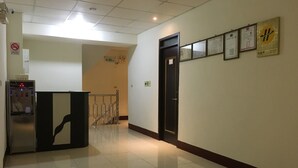 Un pasillo limpio y bien iluminado con dispensador de agua, una puerta de seguridad y un tablón con certificados en la pared.