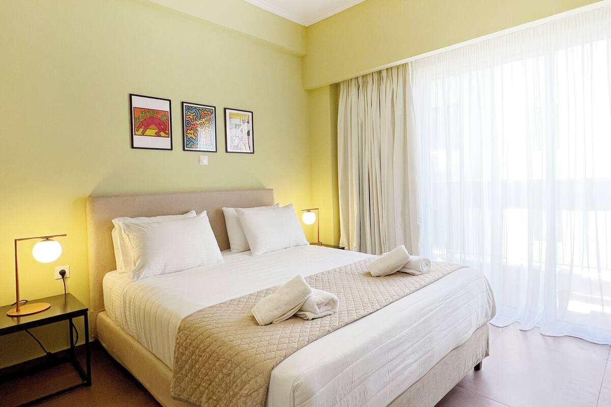 A hotel room with a large bed, two bedside tables with lamps, and three framed artworks on the wall.