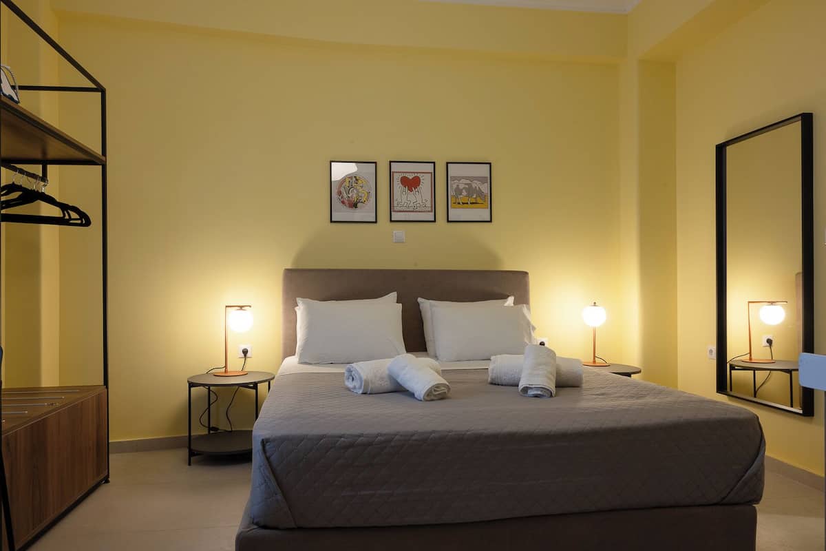 A hotel room with a large bed, two bedside tables with lamps, a wardrobe, and three framed pictures on the wall.