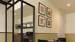 A compact kitchen with a dining area, wooden flooring, and a mirrored partition. - Athens Stories (Athens)