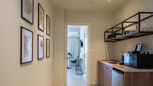 A modern kitchen with a dishwasher, a microwave, and a coffee machine. There are framed artworks on the wall and a dining area visible through an open door. - Athens Stories (Athens)