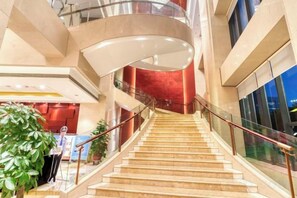 A multi-level interior with a central staircase, glass railings, and a curved ceiling structure. - Geshan Prince Hotel Zhejiang (Hangzhou)