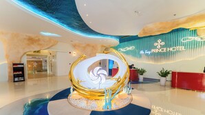 Eine moderne Hotelhalle mit einem zentralen Dekorationsobjekt, einer Rezeption und einem Schild für das Prince Hotel.