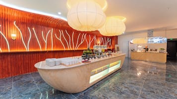 Welcome to our lobby, featuring a sleek reception area with a marble countertop, fruit bowl, coffee station, and bottled water.