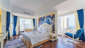 A hotel room with a large bed, a desk, a chair, and a view of the city. - Nha VIET Nha Trang Hotel (Nha Trang)