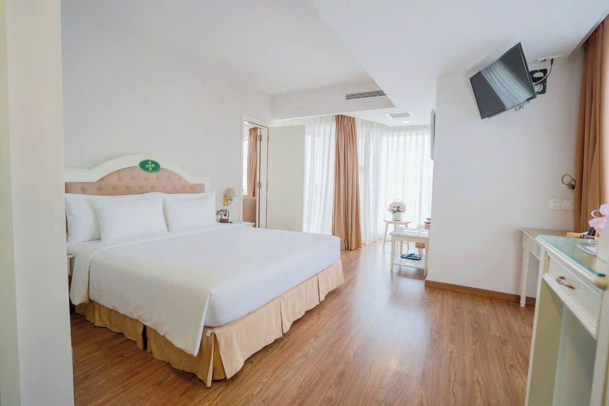 Een hotelkamer met een groot bed, een aan de muur bevestigde televisie en een bureau met een stoel.