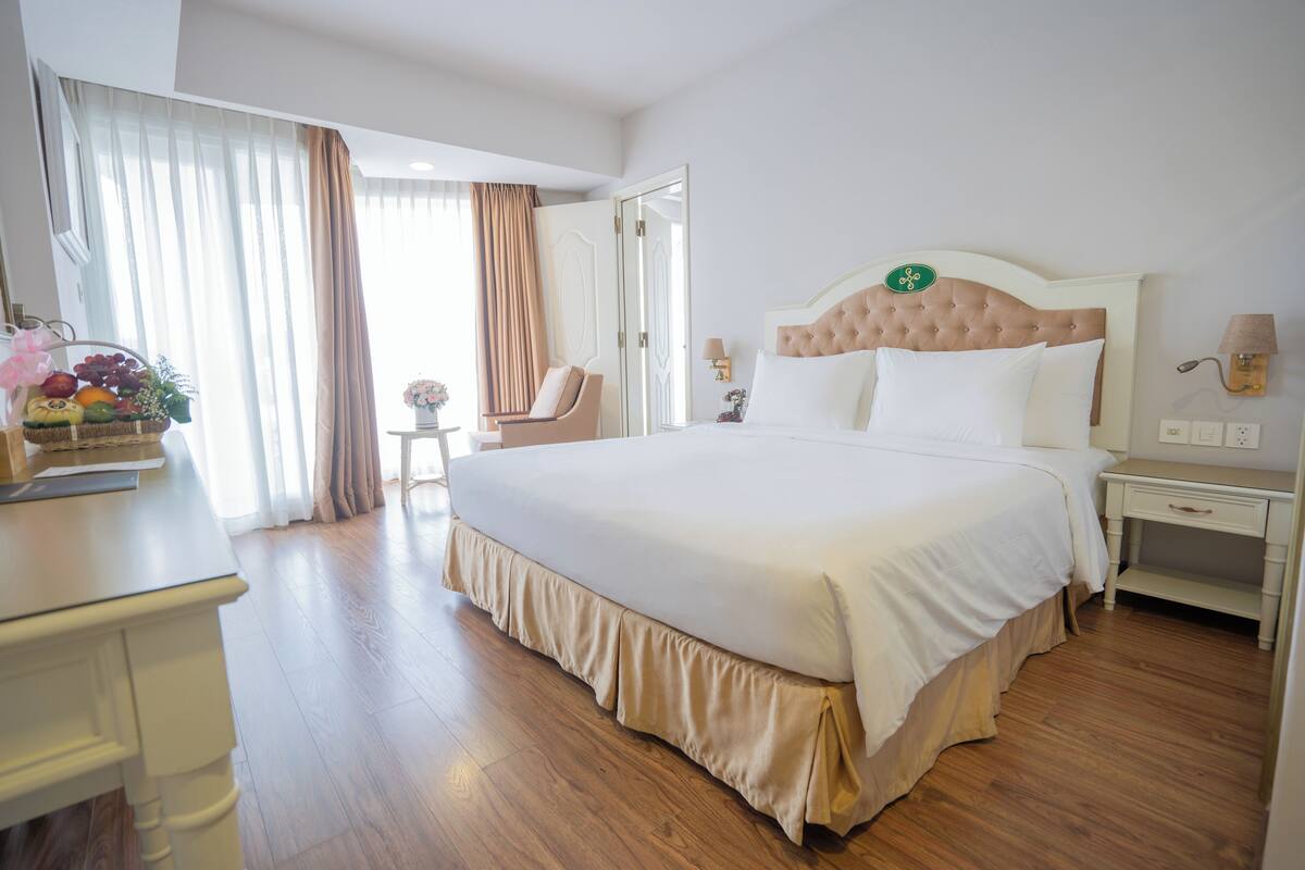 Een hotelkamer met een groot bed, een nachtkastje, een stoel en een bureau met een fruitmand.