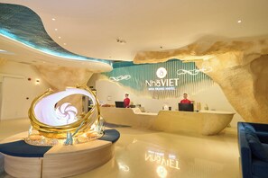 A hotel reception area with a modern design, featuring a reception desk, a digital display, and a unique ceiling structure. - Nha VIET Nha Trang Hotel (Nha Trang)