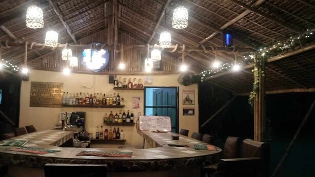 A rustic bar area with wooden ceiling, hanging lights, and a bar counter with bottles. - Hidaway Resort (San Antonio)