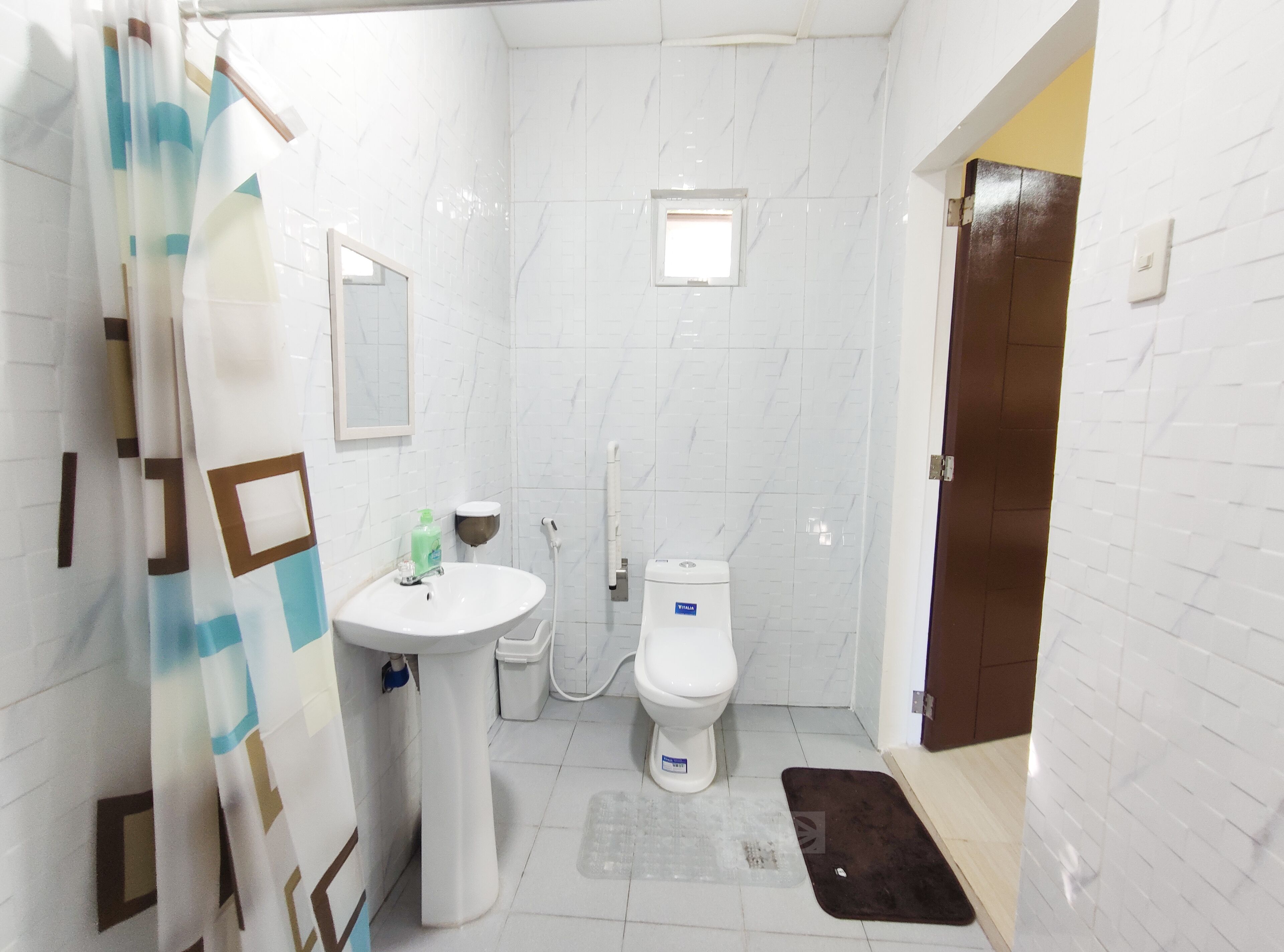 Un baño con lavamanos blanco, inodoro y zona de ducha.