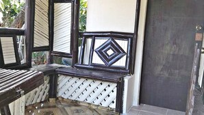 A room with a tiled floor, a bench, a window with a decorative frame, and a door. - Hidaway Resort (San Antonio)