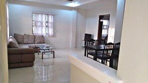 A living room with a sofa, coffee table, and dining table with chairs. - Hidaway Resort (San Antonio)