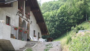 A rustic chalet with a sloped roof, stone walls, and a balcony with potted plants. - Agriturismo Cascina Cornella (Cremeno)