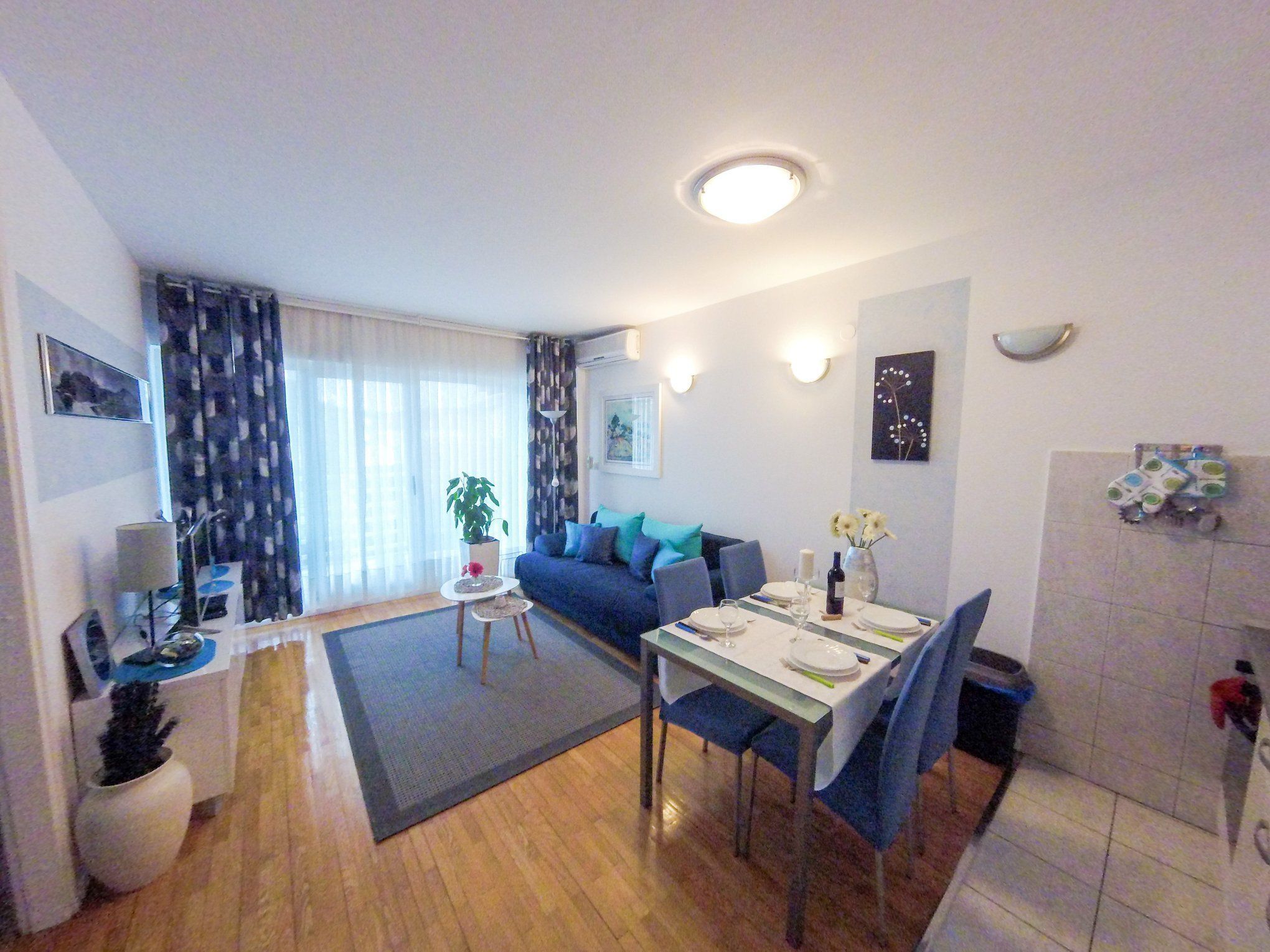 Ett kompakt bostadsutrymme med en matplats, en soffa, ett litet bord och ett köksutrymme.