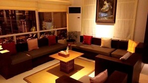 A modern living room with a sofa set, a coffee table, and a painting on the wall. - Golden Guest Hotel Dawei (Dawei)