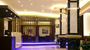 A hotel reception area with a modern design, featuring a reception desk, a seating area, and a decorative wall with vertical panels. - Golden Guest Hotel Dawei (Dawei)