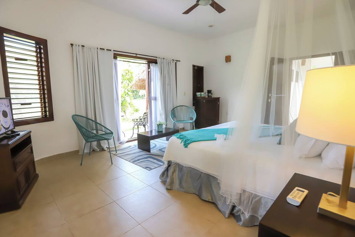 Ein Hotelzimmer mit Bett, Schreibtisch, Stuhl, Kleiderschrank und Deckenventilator.