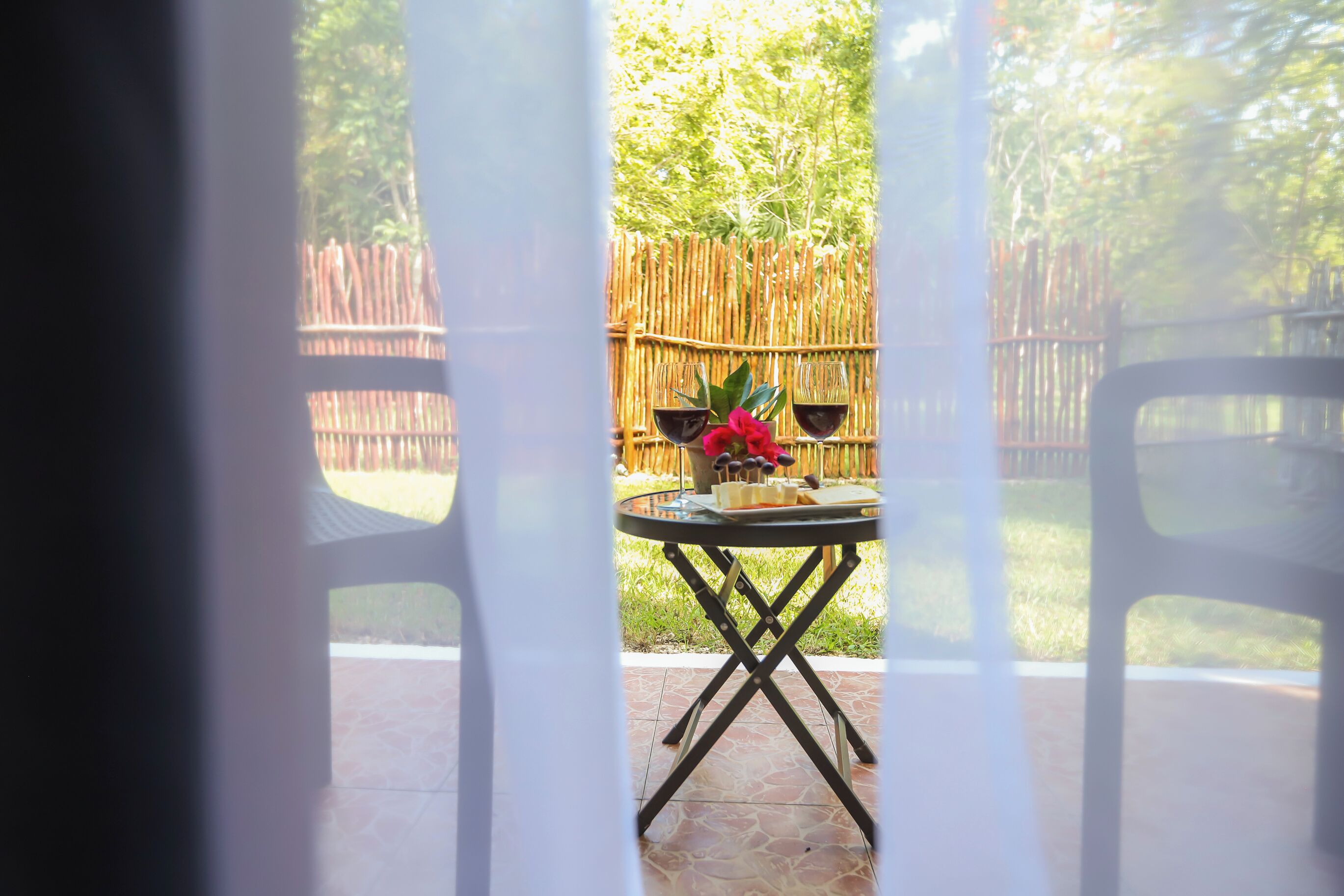 Un patio con mesa lista para dos, cerca de bambú y vistas a un jardín.
