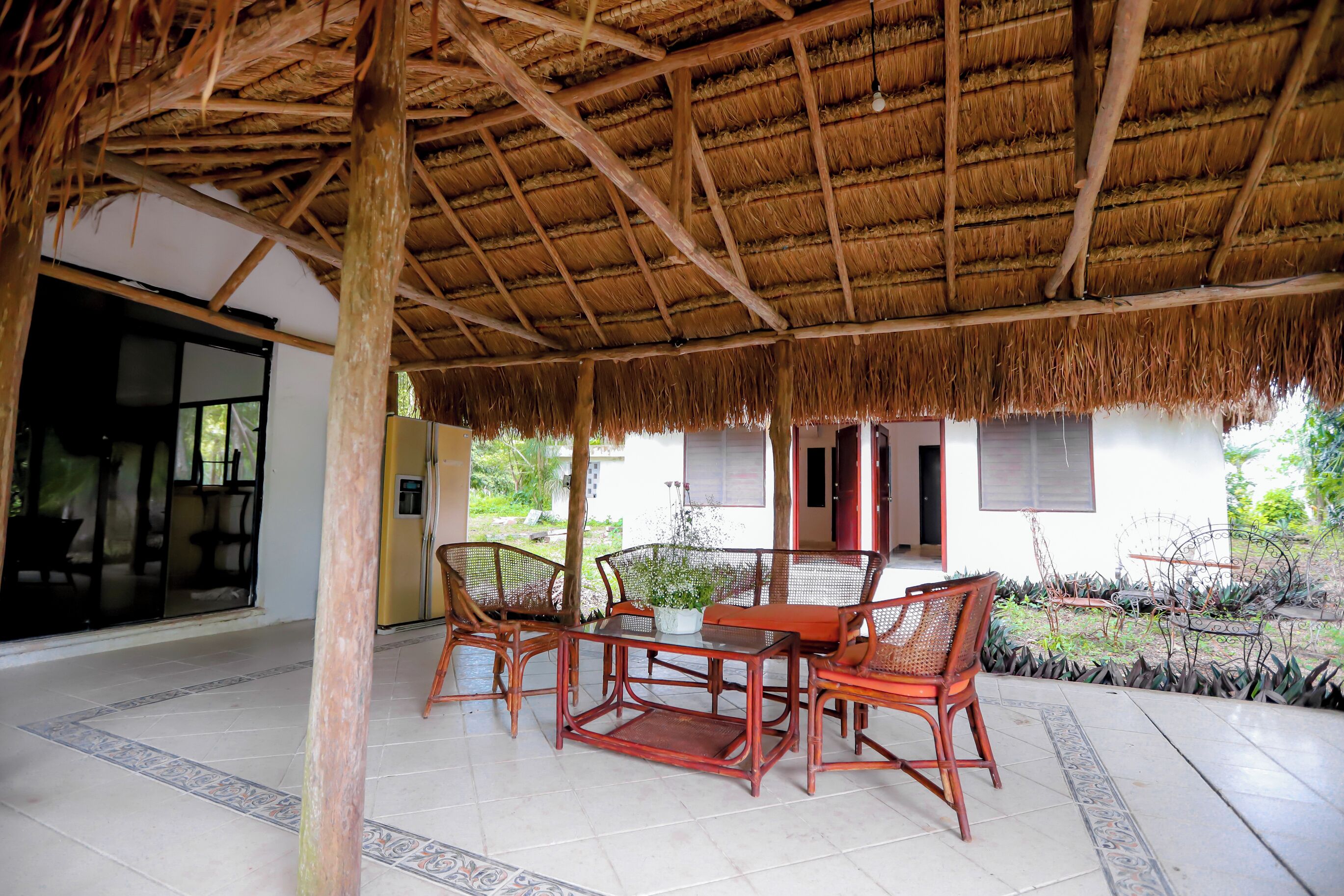 A covered outdoor seating area with wicker furniture and a thatched roof.
