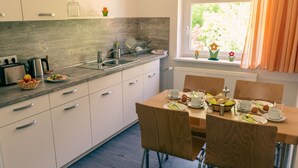 Een moderne keuken met witte kasten, een houten aanrechtblad en een eethoek met een tafel gedekt voor twee personen.