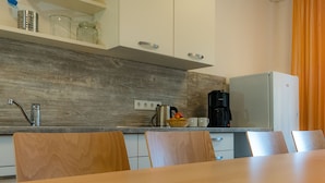 Een moderne keuken met houten kastjes, een roestvrijstalen spoelbak en een eethoek met een houten tafel en stoelen.