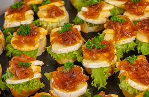 Een schaal met voorgerechtjes, waaronder eiergerechten, overgoten met rode saus en versierd met peterselie.