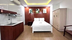 A bedroom with a bed, bedside table, wardrobe, and a kitchenette area with a sink and countertop. - The Samson Boutique Hotel (Da Nang)