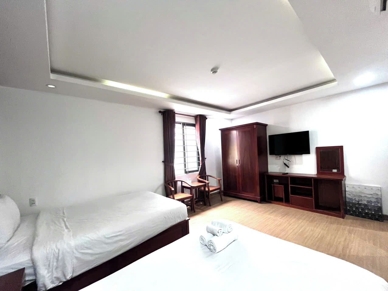A hotel room with a bed, a desk, a chair, a TV, and a wardrobe.