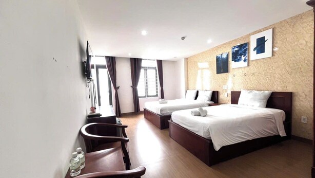 A hotel room with two beds, a desk, a chair, and a TV mounted on the wall. - The Samson Boutique Hotel (Da Nang)