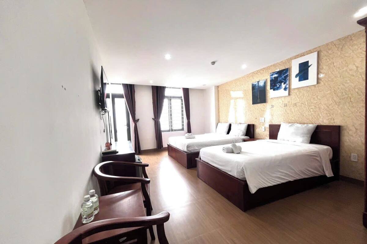 A hotel room with two beds, a desk, a chair, and a TV mounted on the wall.