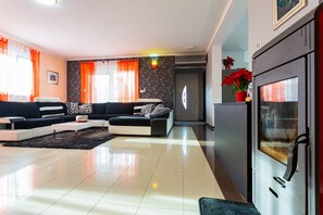 A modern living room with a sectional sofa, a flat-screen TV, and a kitchen area with a refrigerator.