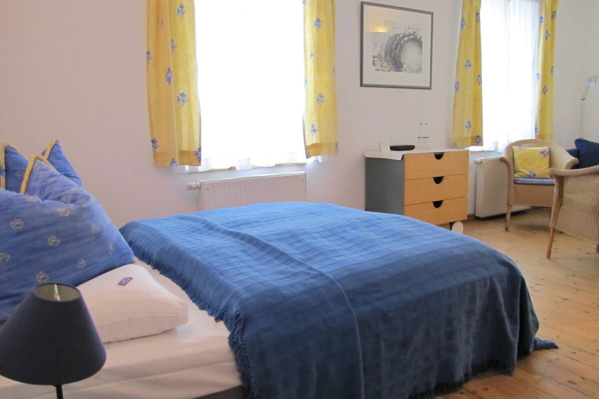 A bedroom with a bed, a desk, a chair, and a radiator.