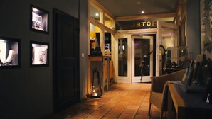 Eine Hotelhalle mit gefliestem Boden, einer Rezeption und einer Treppe zu den Zimmern.