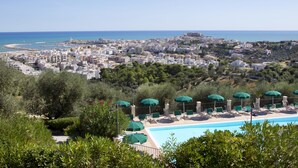 Un resort con piscina, sillas de descanso y sombrillas.