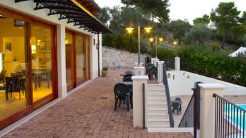 A patio area with outdoor seating, a pool, and a stone wall.