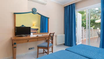 Een hotelkamer met een houten bureau, een stoel, een televisietoestel en twee bedden.