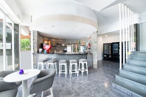 A bar area with a stone wall, bar stools, and a Coca-Cola sign. - Nura Condor (Palma de Mallorca)