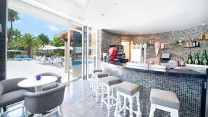 Zona de bar con pared de piedra, taburetes y mostrador con máquina de café.