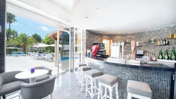 A bar area with a stone wall, seating, and a view of the outdoor pool.