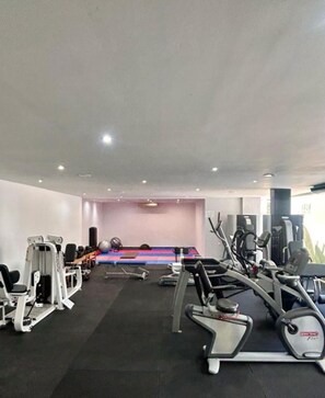Une salle de sport équipée de divers appareils d’exercice, notamment des tapis de course et des appareils de musculation.
