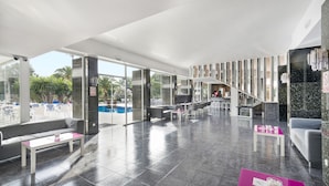 Un vestíbulo moderno con vista a la piscina, zonas de estar y una escalera que conduce a los pisos superiores.