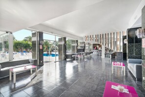 A modern lobby with a pool view, seating areas, and a staircase leading to upper floors. - Nura Condor (Palma de Mallorca)