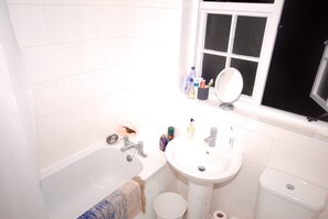 Ein Badezimmer mit Badewanne, Waschbecken und Toilette. Auf dem Waschbecken stehen Pflegeprodukte.