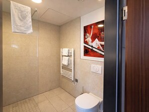 A modern bathroom with a shower, a toilet, and a towel rack.