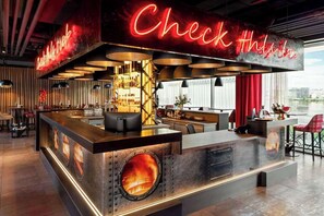 A modern bar area with a neon sign, a central bar counter, and seating arrangements.