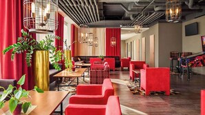 Un restaurante moderno con asientos rojos, detalles dorados y tuberías industriales en el techo.