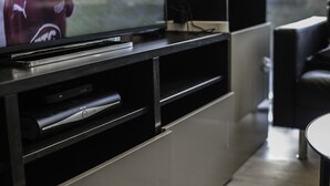A modern living room with a flat-screen TV on a black entertainment unit, a sleek sofa, and a minimalist design. - MD Luxury Apartment (London)